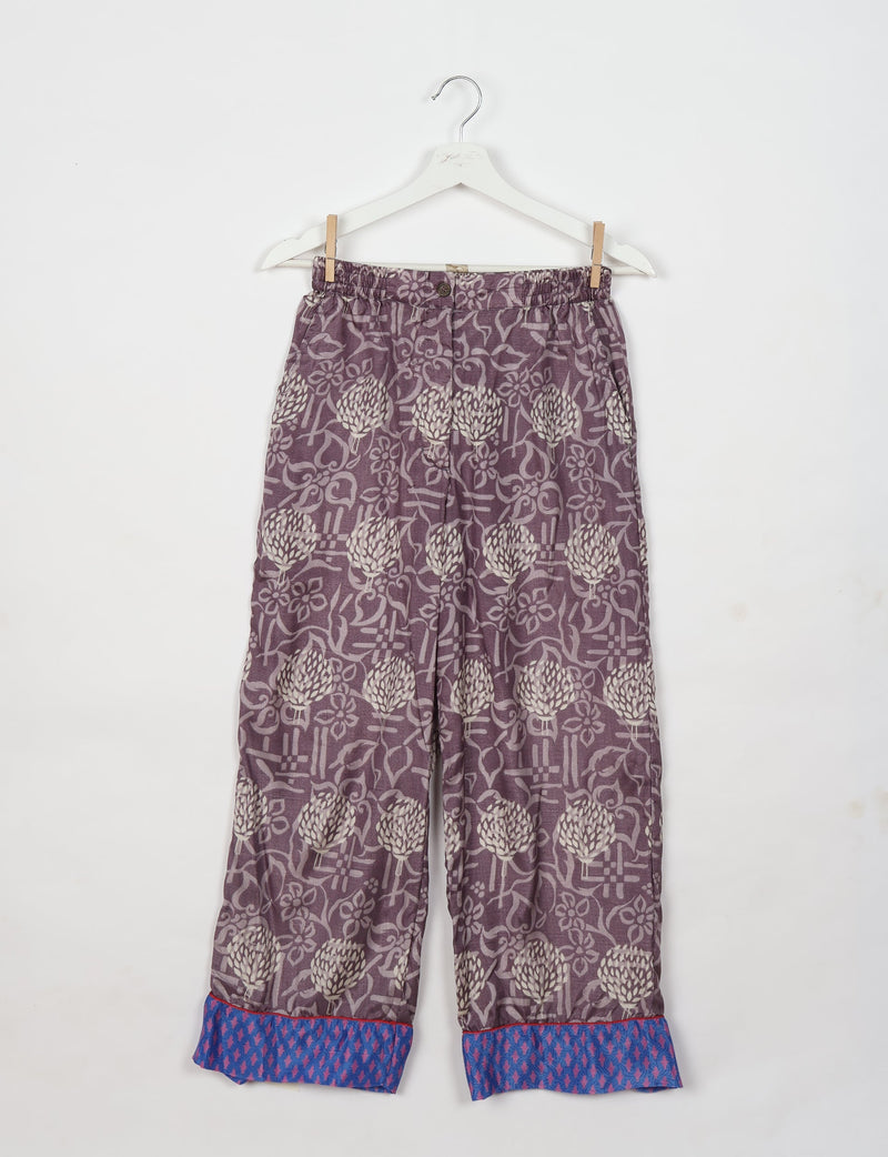 Purple floral pajama pants with blue patterned cuffs, elastic waistband, and button front, hanging on white hanger