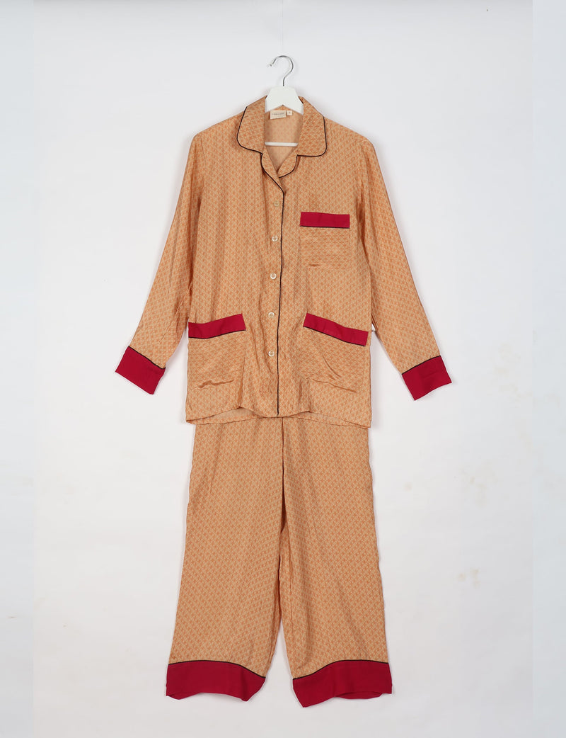 Beige long-sleeve pajama set with micro pattern, red cuffs, pocket trims, black piping, hanging on white hanger, front view