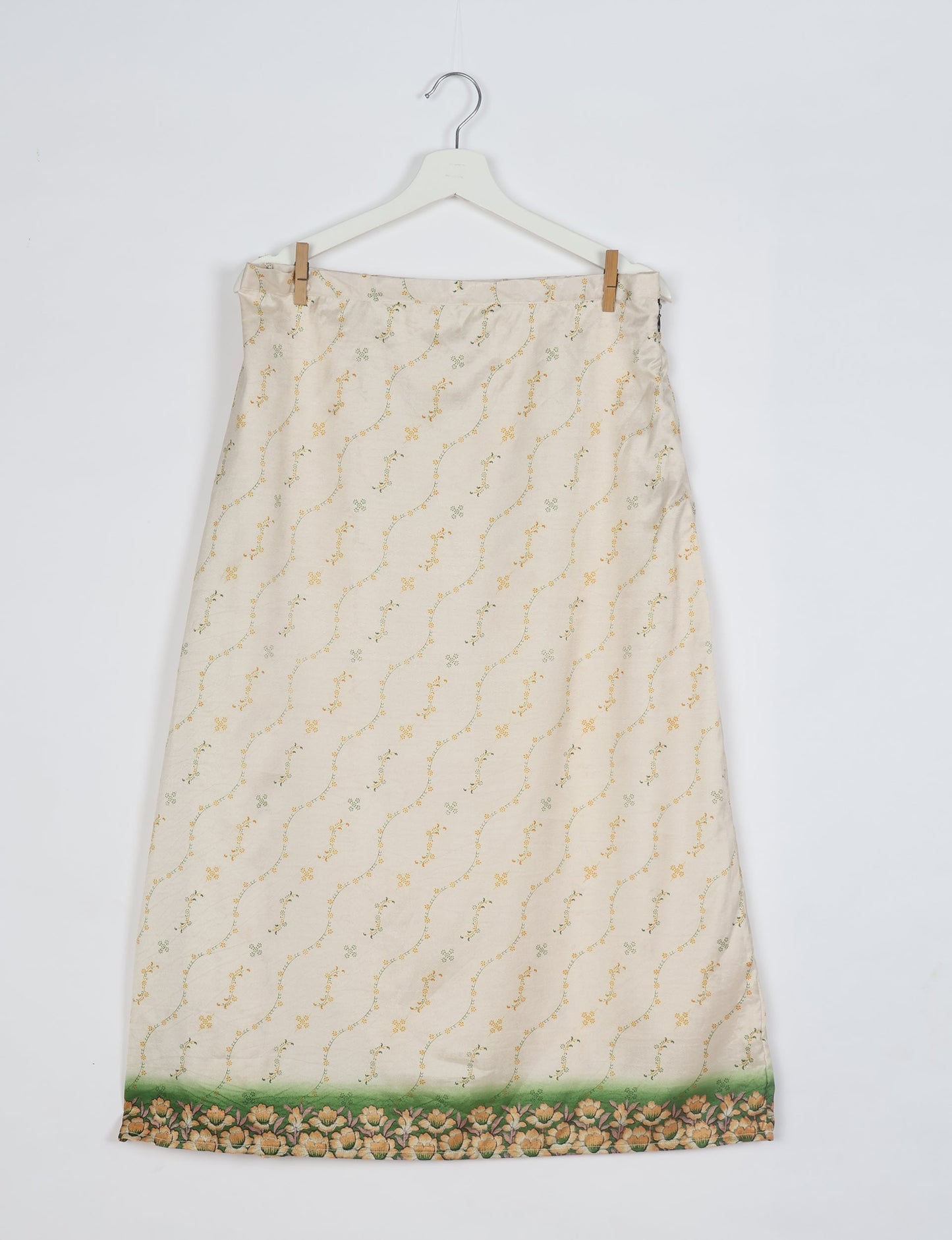 White A-line skirt with small yellow and green floral print and green floral border at hem, hanging on white hanger
