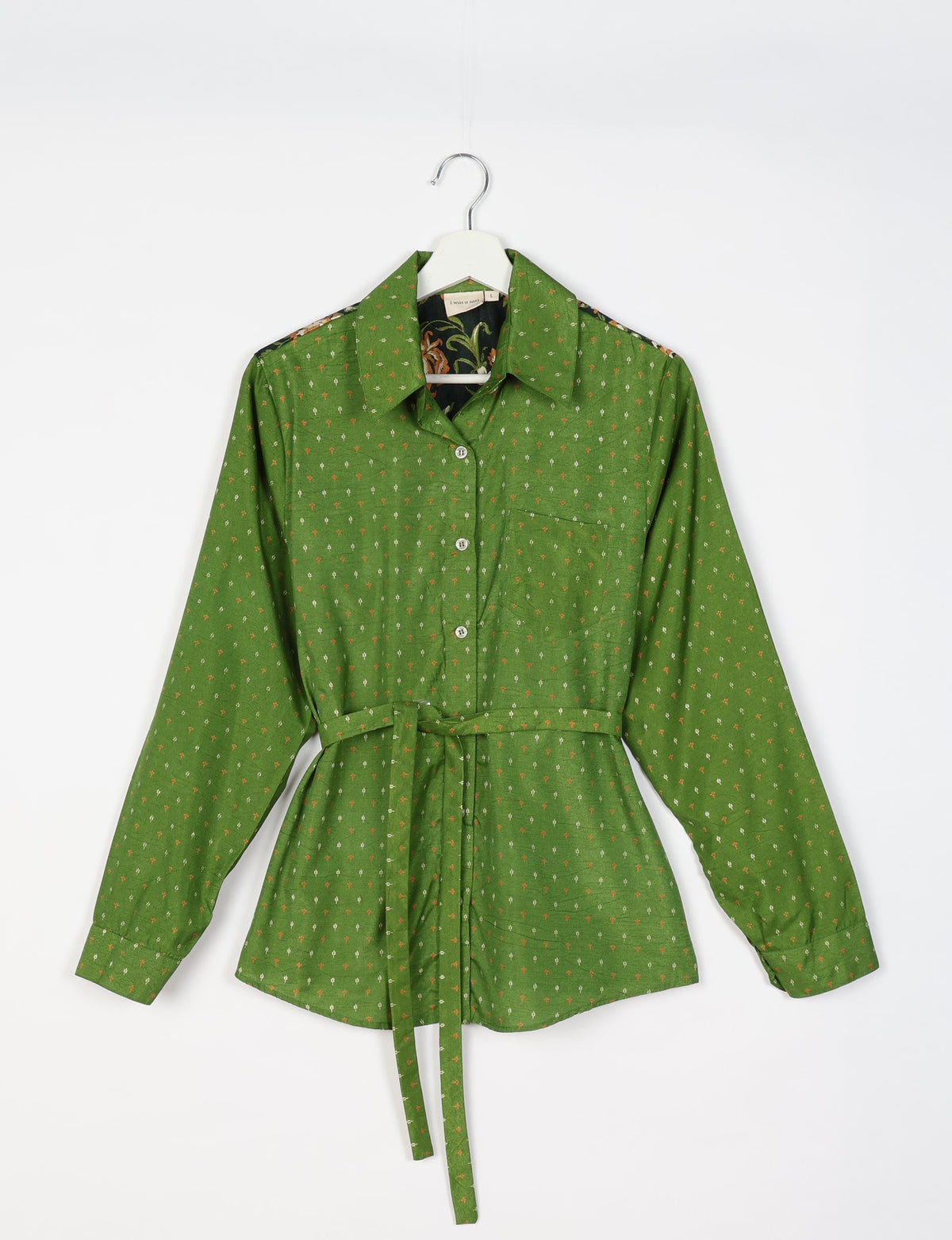 Green long-sleeve button-up shirt with small white and orange micro print, chest pocket, and waist tie belt, front view on