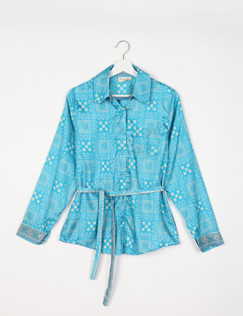 Blue Indian ethnic shirt with white geometric patterns, long sleeves, collar, and a matching fabric belt, hanging on a white hanger
