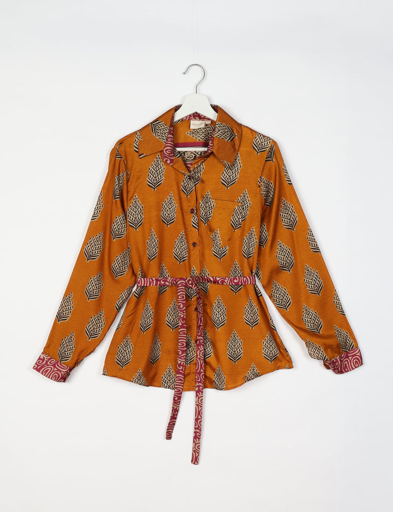 Orange long-sleeve button-up shirt with black and beige leaf print, maroon patterned collar, cuffs, and waist tie, front pocket
