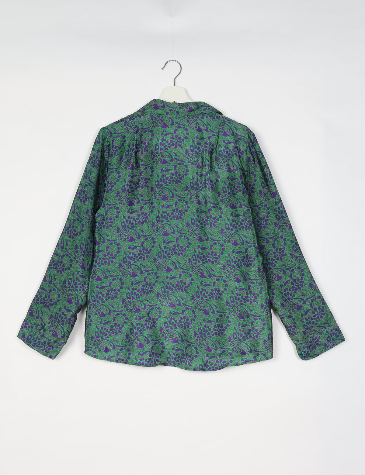 Green long-sleeve shirt with purple tropical floral pattern, shown from back, hanging on white hanger against white background