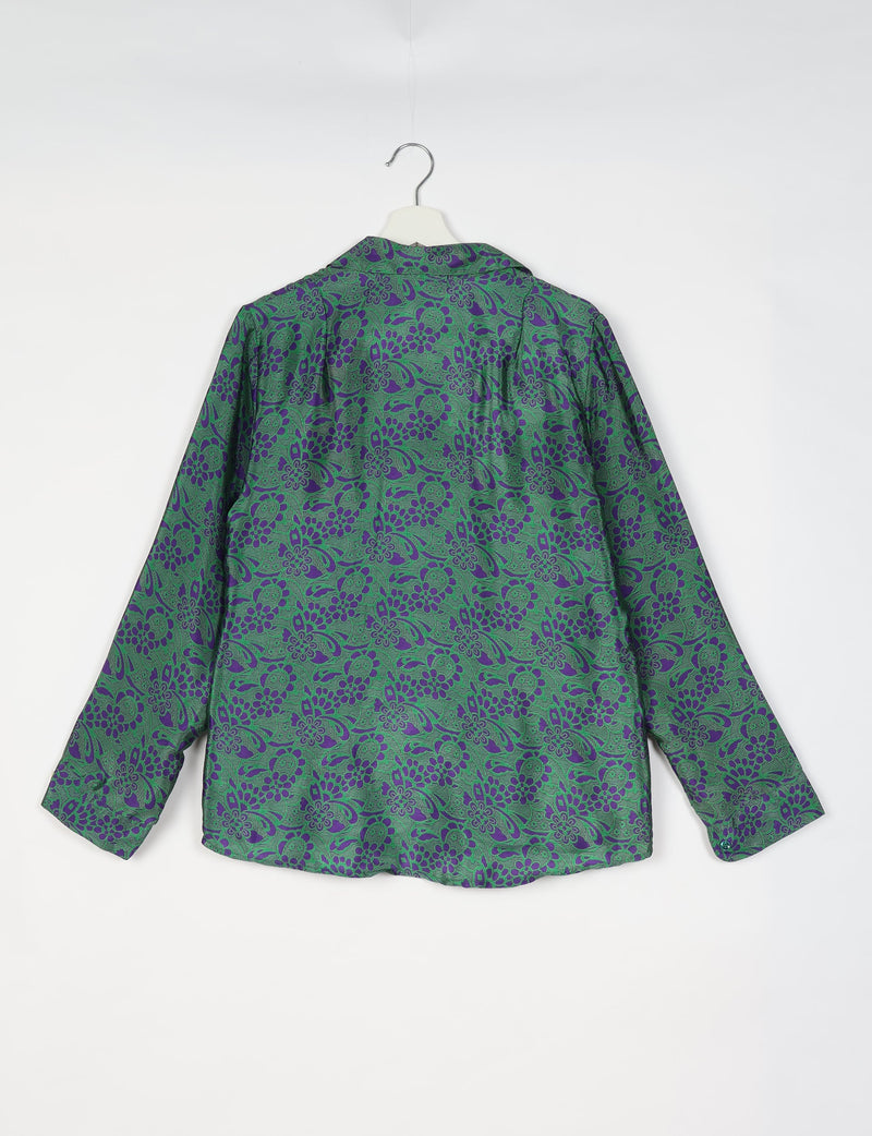 Green long-sleeve shirt with purple tropical floral pattern, shown from back, hanging on white hanger against white background