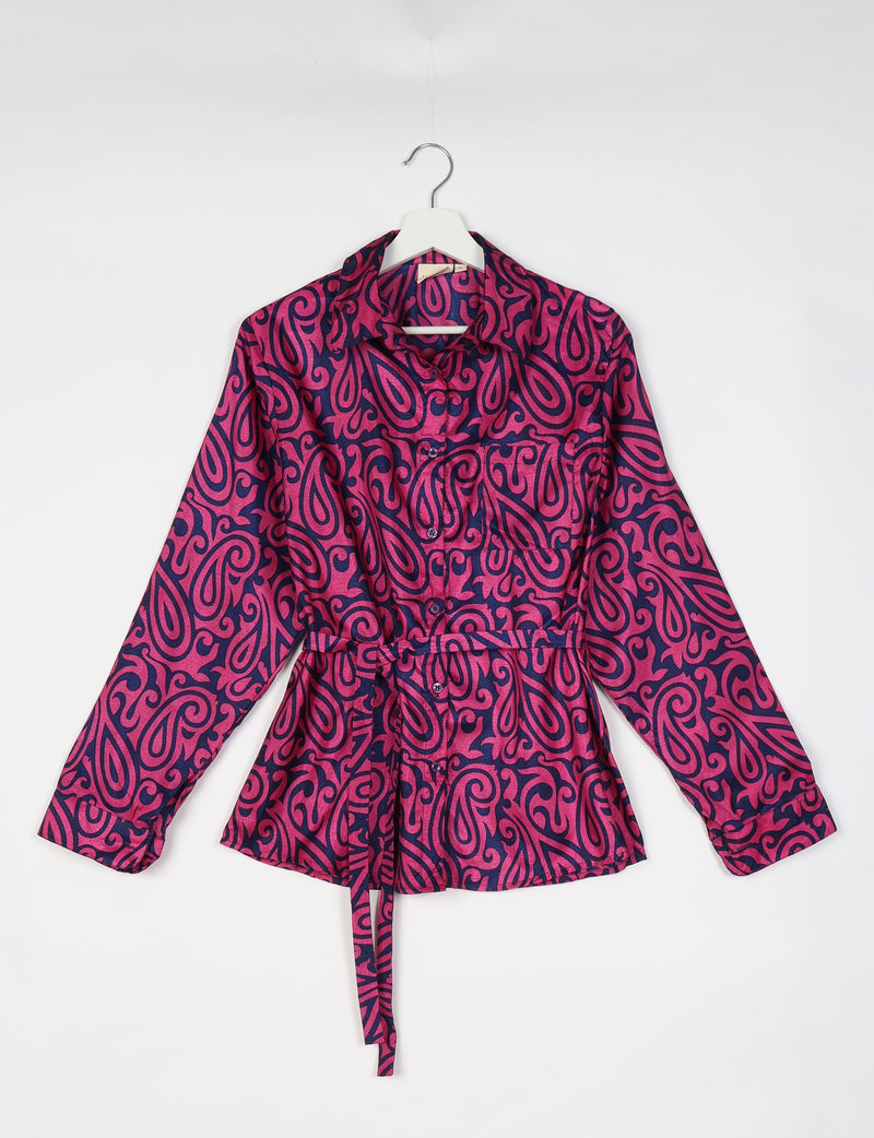 Pink paisley patterned long-sleeve button-up shirt with collar and waist tie, shown hanging on white hanger