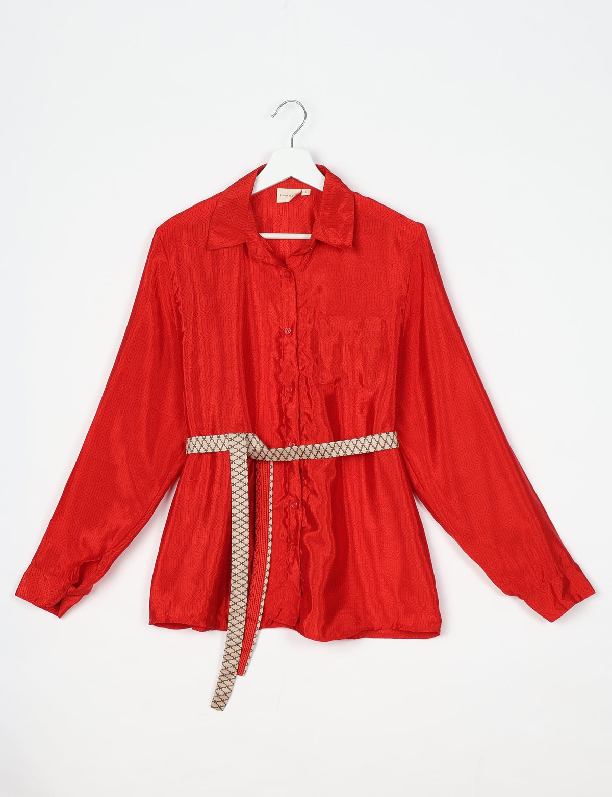 Red long-sleeve button-up shirt with subtle geometric pattern and beige patterned belt, front view on white hanger
