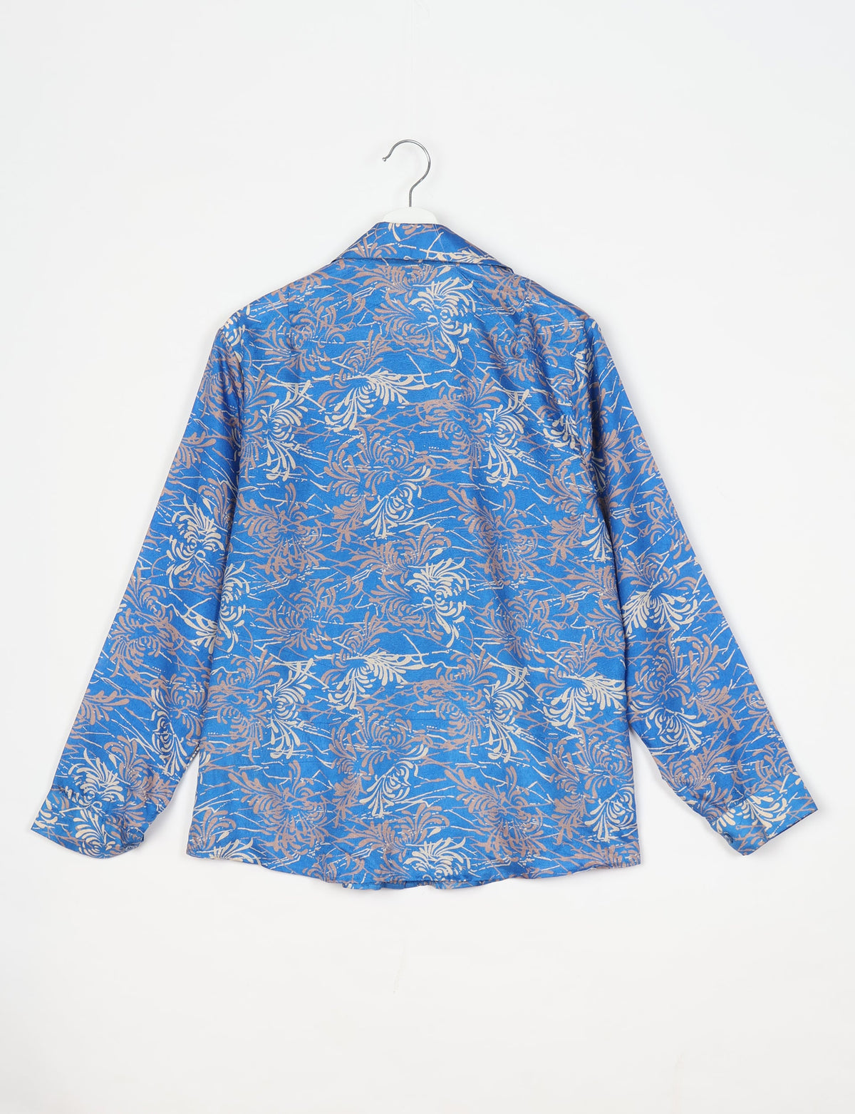 Blue long-sleeve shirt with beige and white abstract floral pattern, shown from back on white hanger against white background