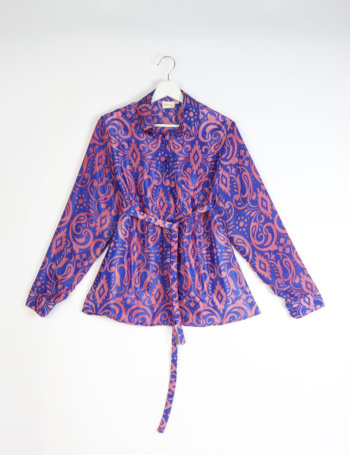 Blue and pink paisley patterned long-sleeve shirt with collar and front buttons hanging on white hanger