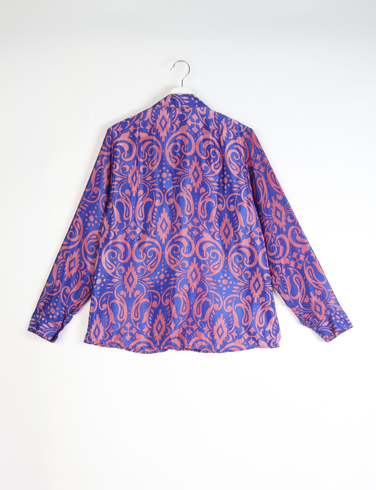 Blue shirt with pink paisley pattern, long sleeves, and buttoned cuffs, shown from back on a hanger