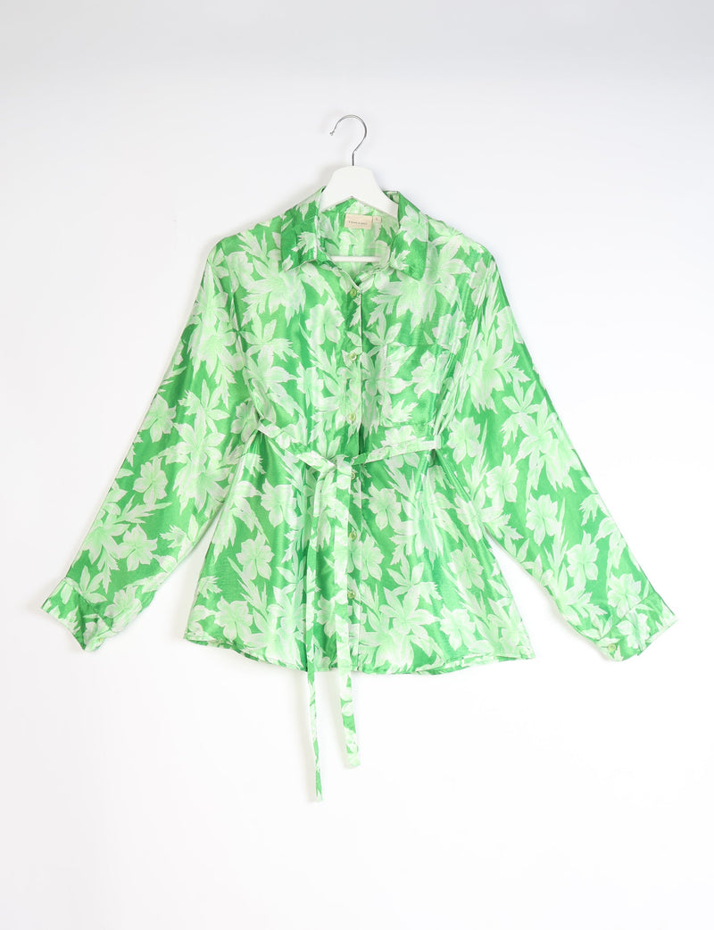 Green button-up shirt with light green leaf pattern, long sleeves, chest pocket, collar, and waist tie, hanging on white hanger