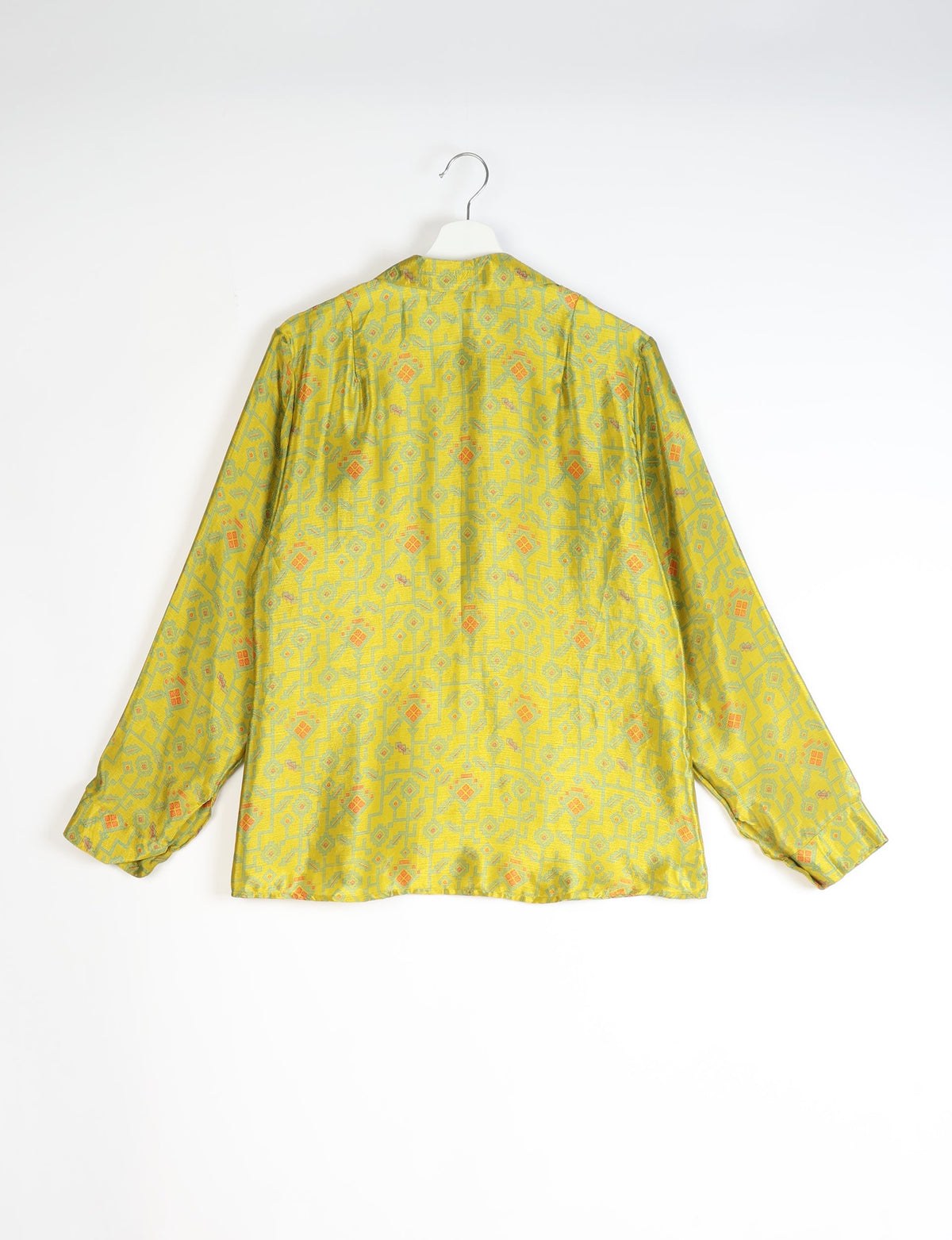 Yellow long-sleeve shirt with abstract geometric pattern in green and orange, shown from back on white hanger