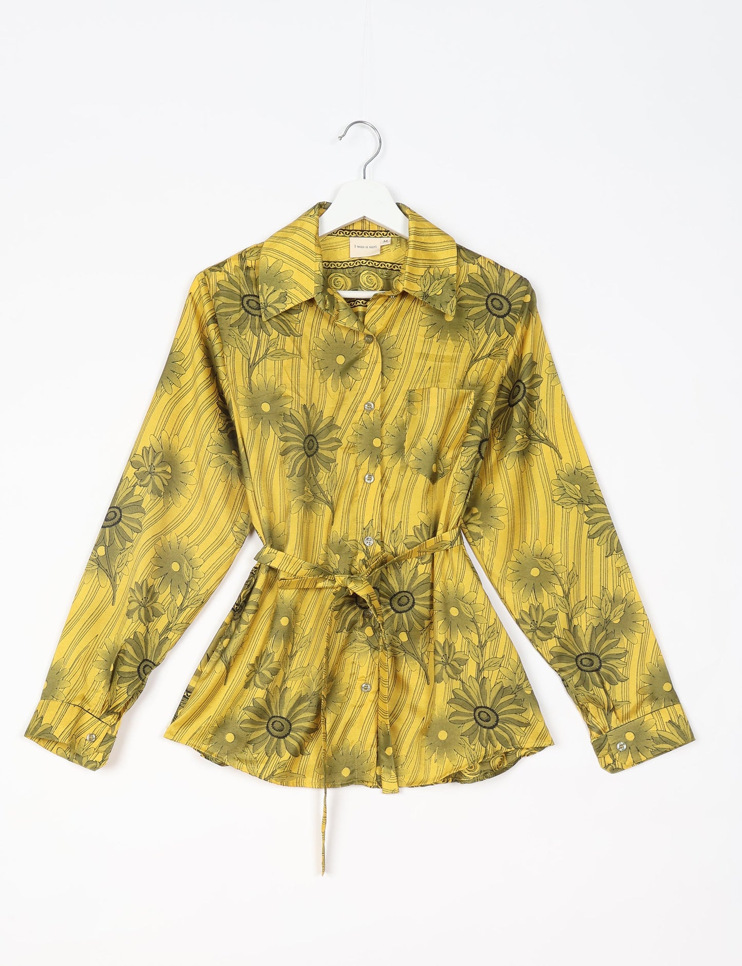 Experience sustainable fashion with our classic slim-fit shirt, crafted with ethical and green values. The shirt, designed for minimal waste, features a tie-up waist belt or neck tie, semi-spread collar, and regular shirt cuffs. Versatile and eco-friendly, wear it tucked in, unbuttoned over a tank top, or knotted at the waist for a unique style.
