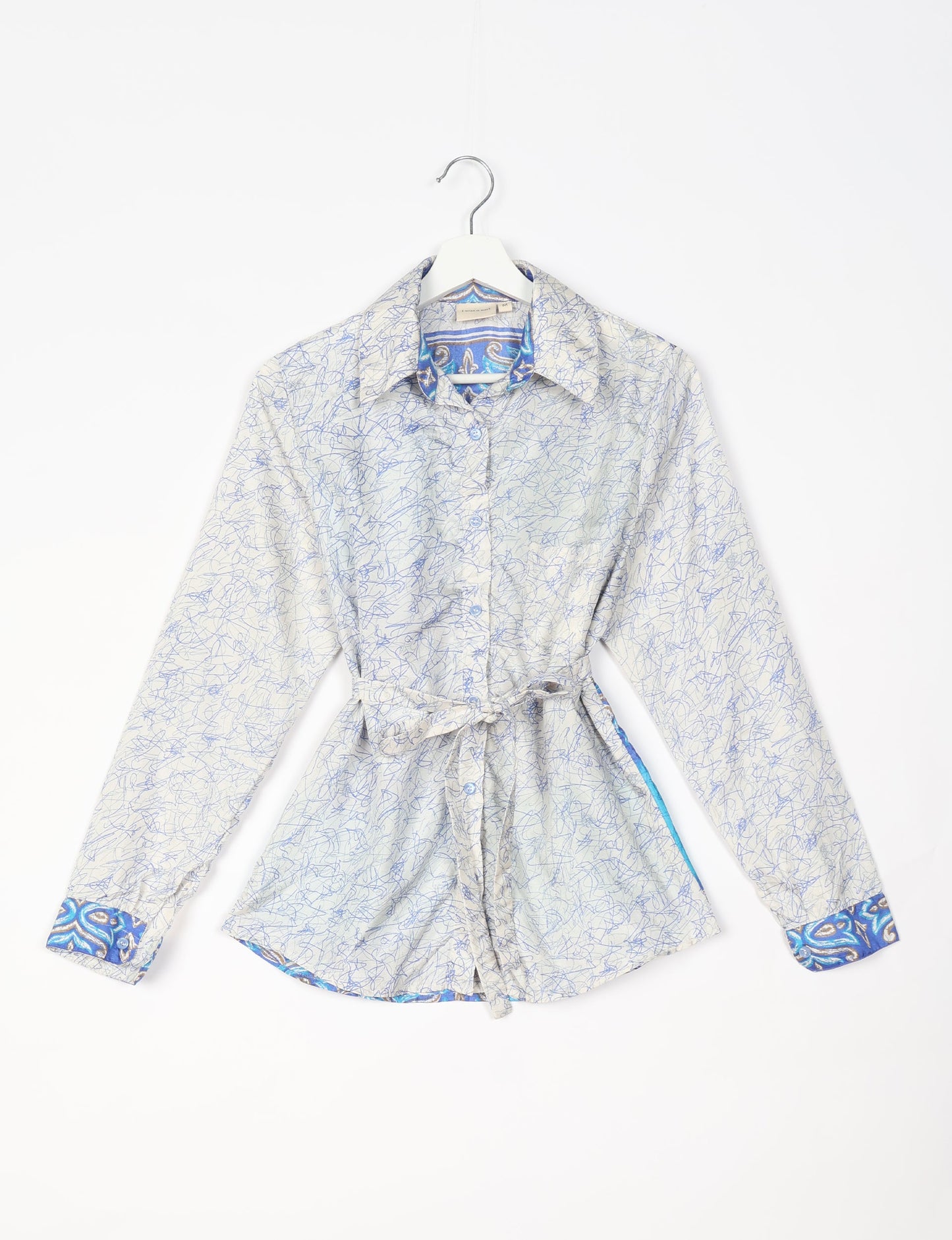 Experience sustainable fashion with our classic slim-fit shirt, crafted with ethical and green values. The shirt, designed for minimal waste, features a tie-up waist belt or neck tie, semi-spread collar, and regular shirt cuffs. Versatile and eco-friendly, wear it tucked in, unbuttoned over a tank top, or knotted at the waist for a unique style.