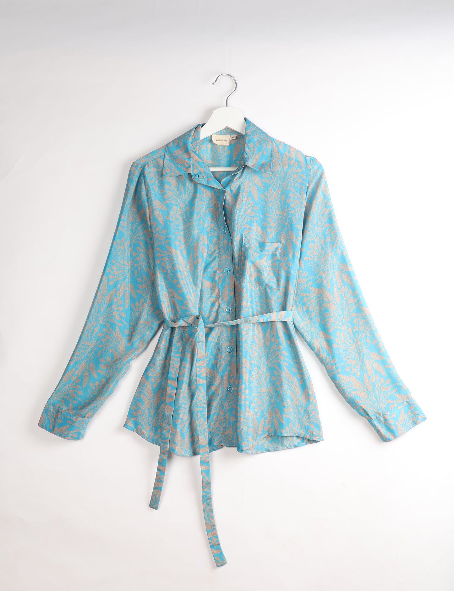 Experience sustainable fashion with our classic slim-fit shirt, crafted with ethical and green values. The shirt, designed for minimal waste, features a tie-up waist belt or neck tie, semi-spread collar, and regular shirt cuffs. Versatile and eco-friendly, wear it tucked in, unbuttoned over a tank top, or knotted at the waist for a unique style.