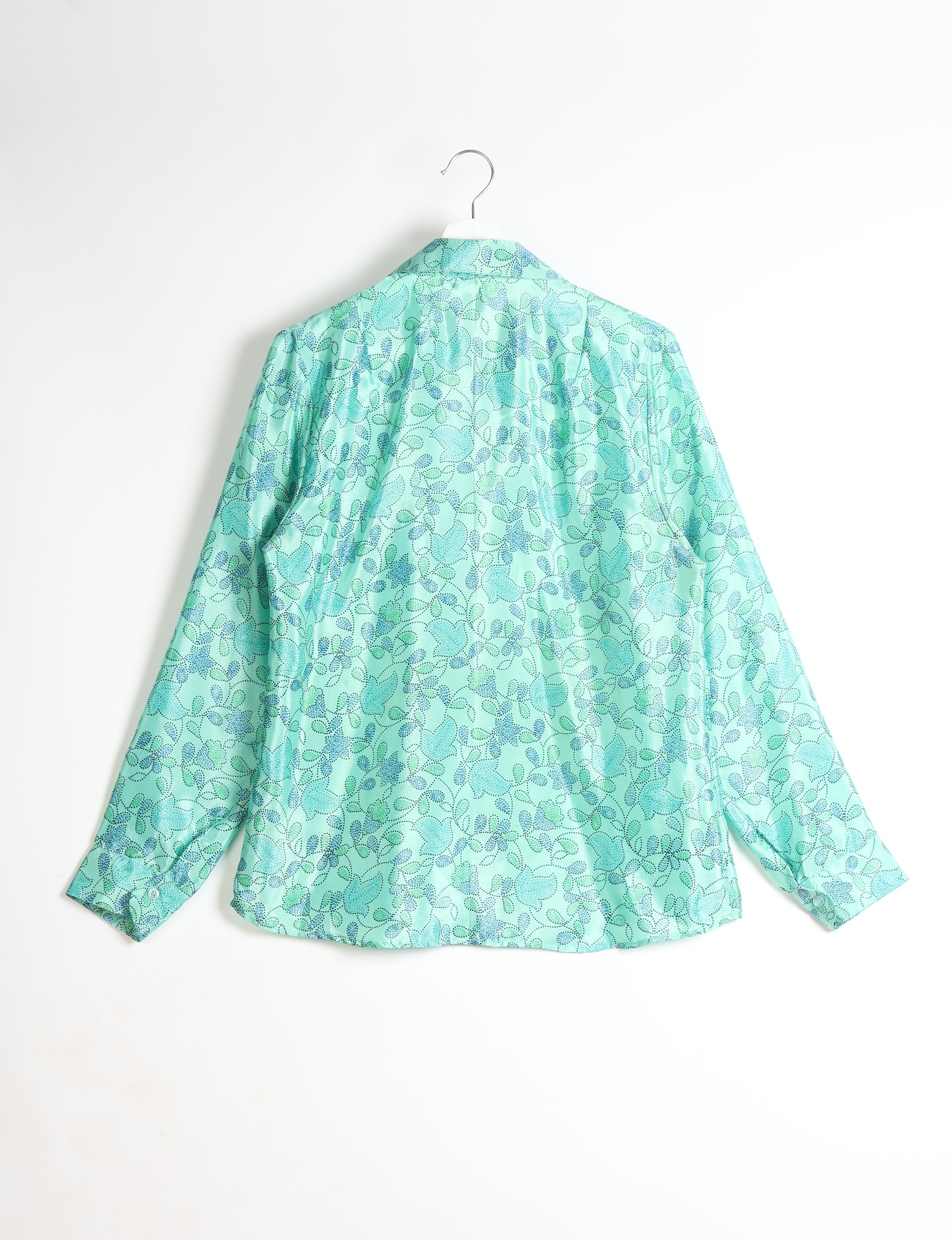 Green long-sleeve shirt with blue and teal tropical leaf pattern, shown from back on white hanger against white background