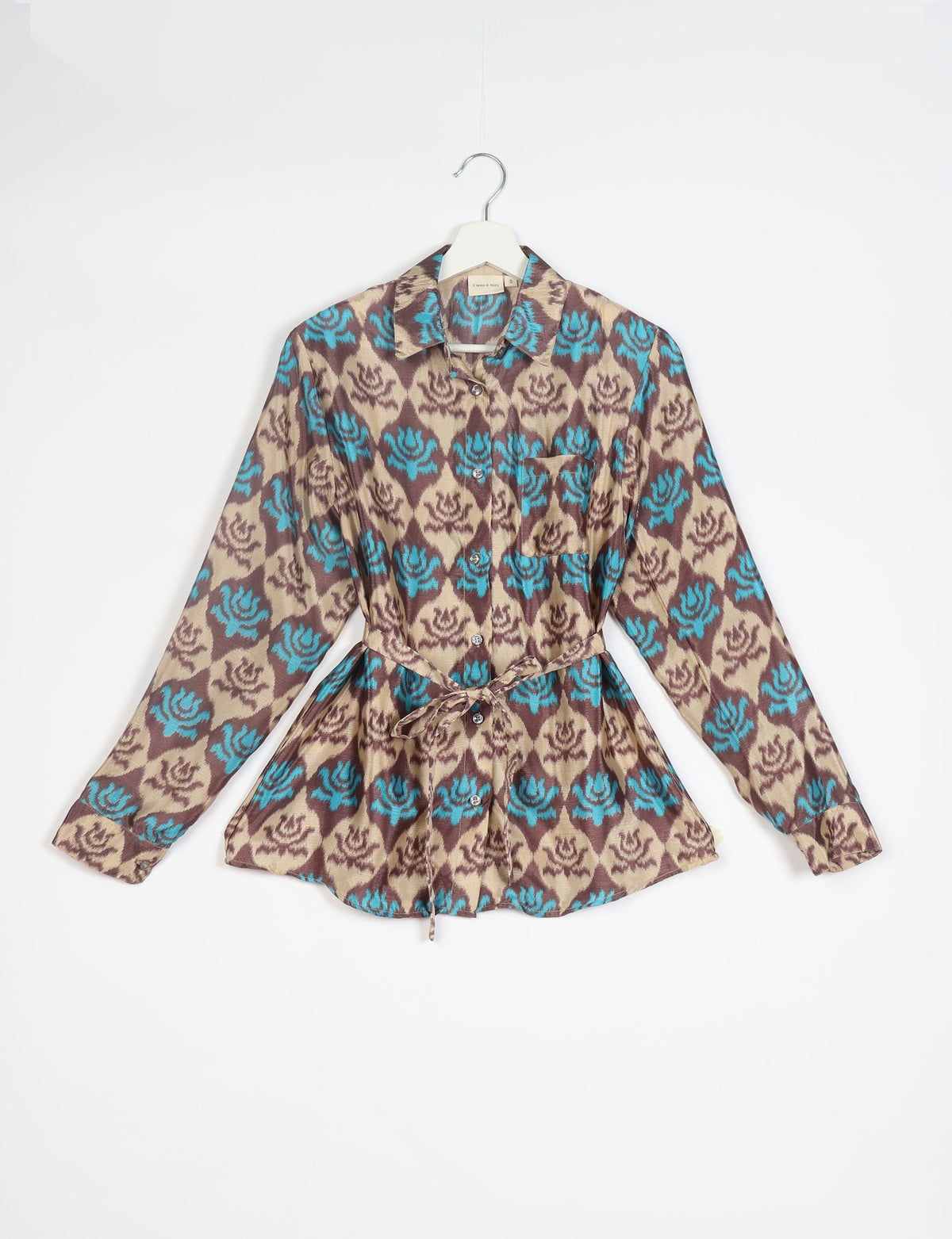 Long-sleeve button-up shirt with blue and brown floral pattern, chest pocket, collar, and waist tie, hanging on white hanger