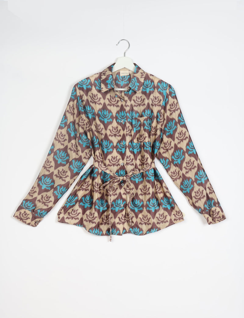 Long-sleeve button-up shirt with blue and brown floral pattern, chest pocket, collar, and waist tie, hanging on white hanger