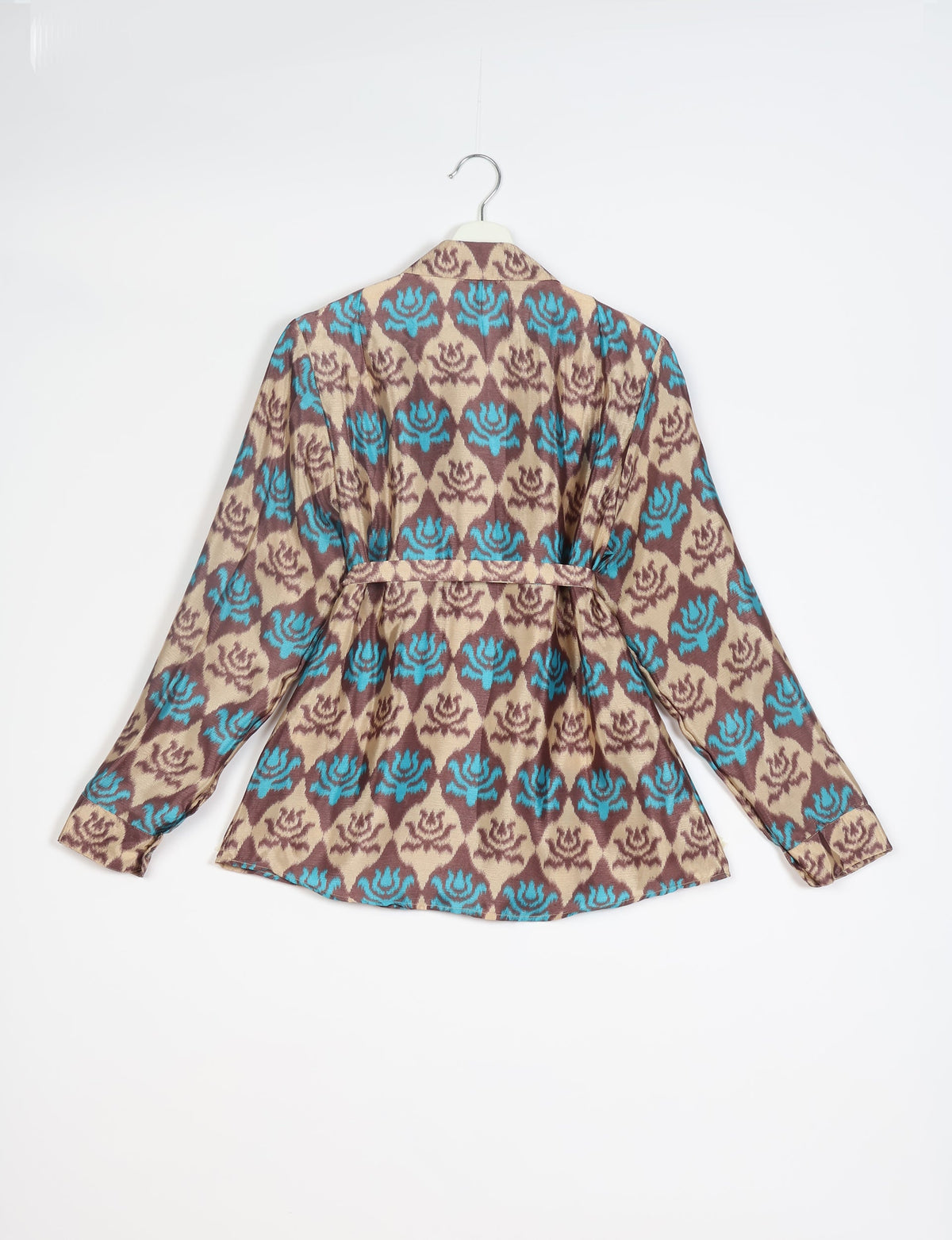Long-sleeve shirt with blue and brown floral pattern on beige background, back view, hanging on white hanger