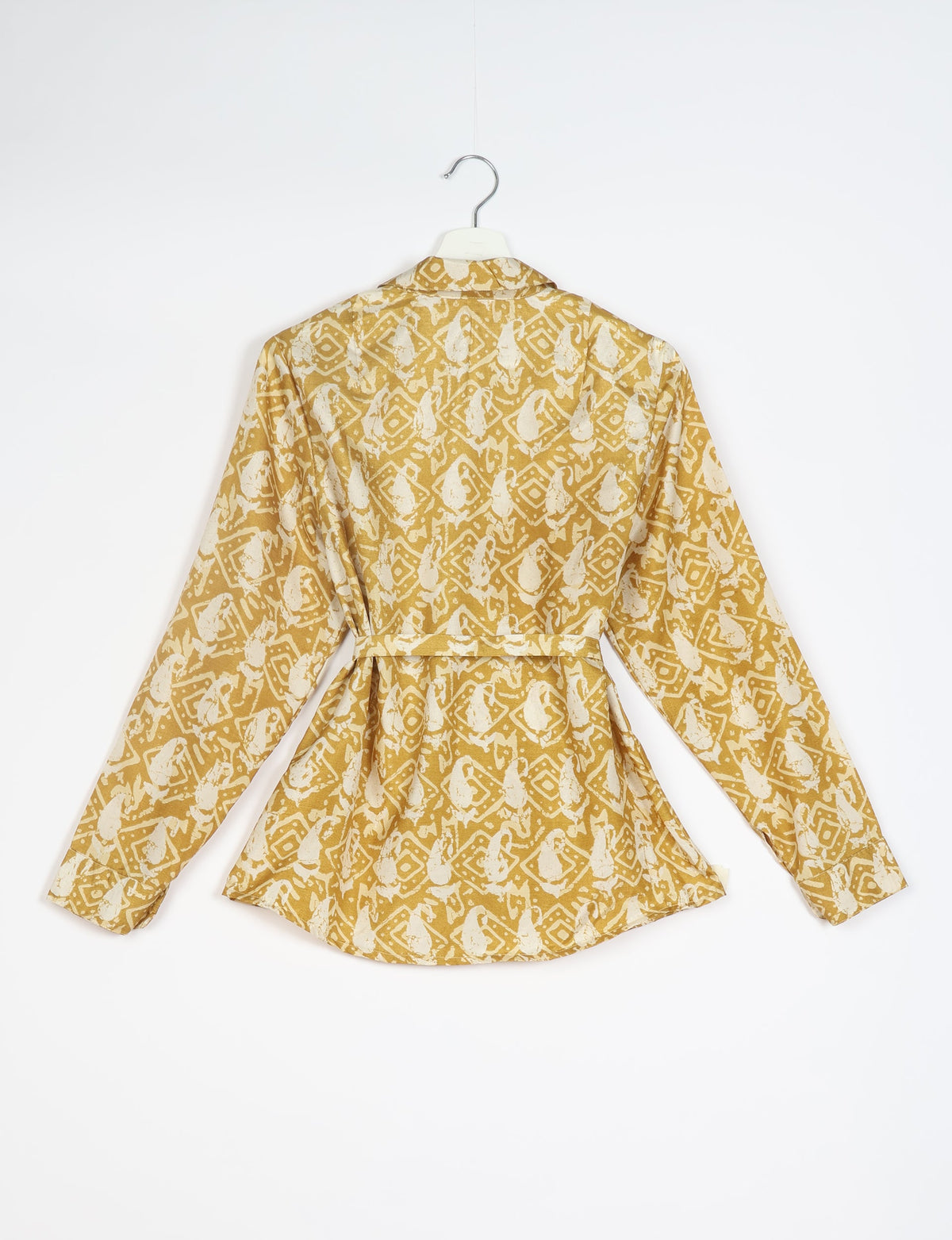 Long-sleeve shirt with beige and white abstract geometric pattern, back view, hanging on white hanger against white background