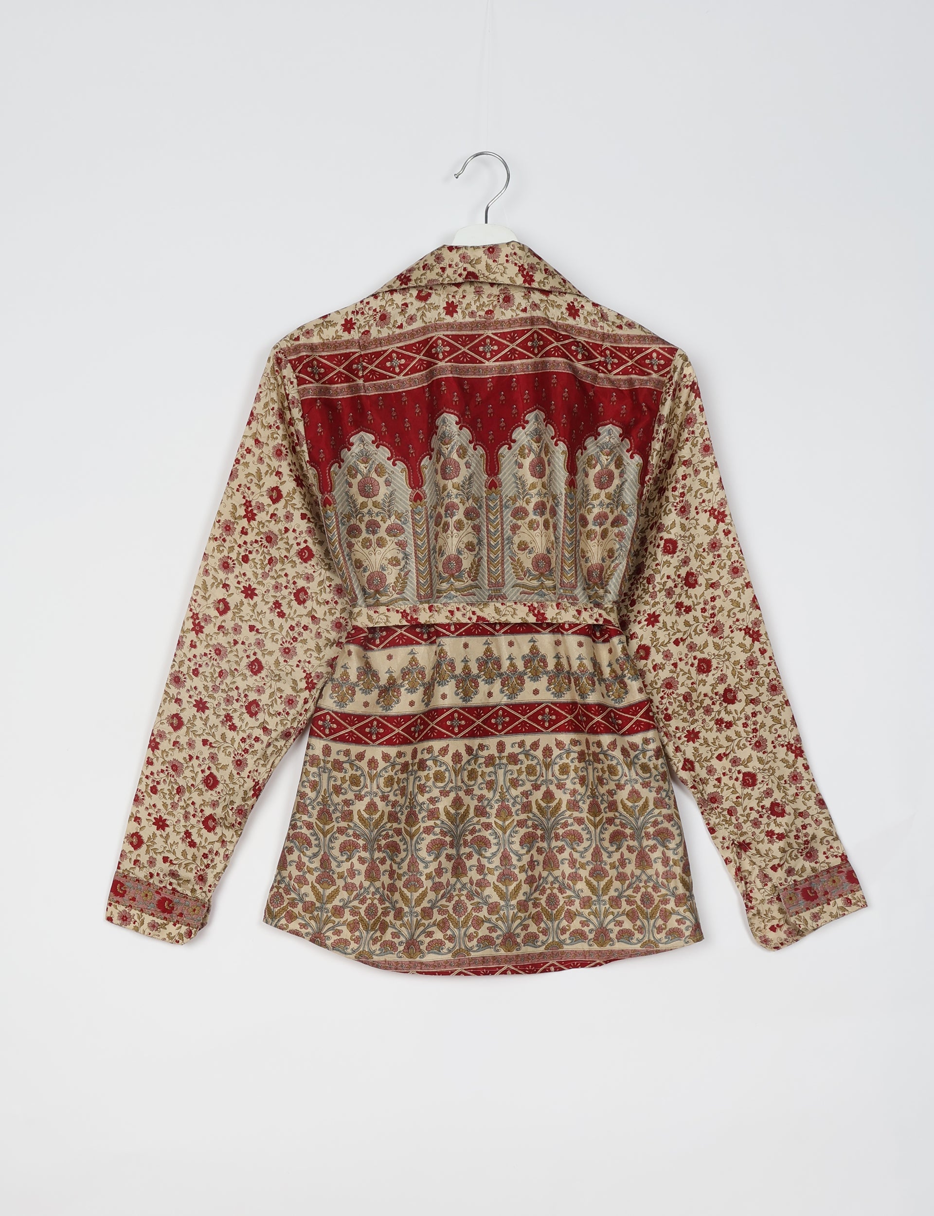Beige long-sleeve shirt with red and multicolor floral and geometric tropical patterns, shown from back on hanger