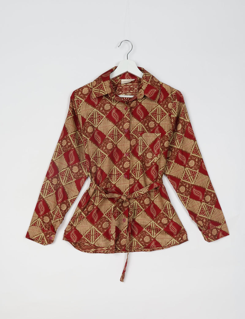 Long-sleeve red shirt with beige geometric and floral patterns, button front, chest pocket, and waist tie, hanging on white hanger