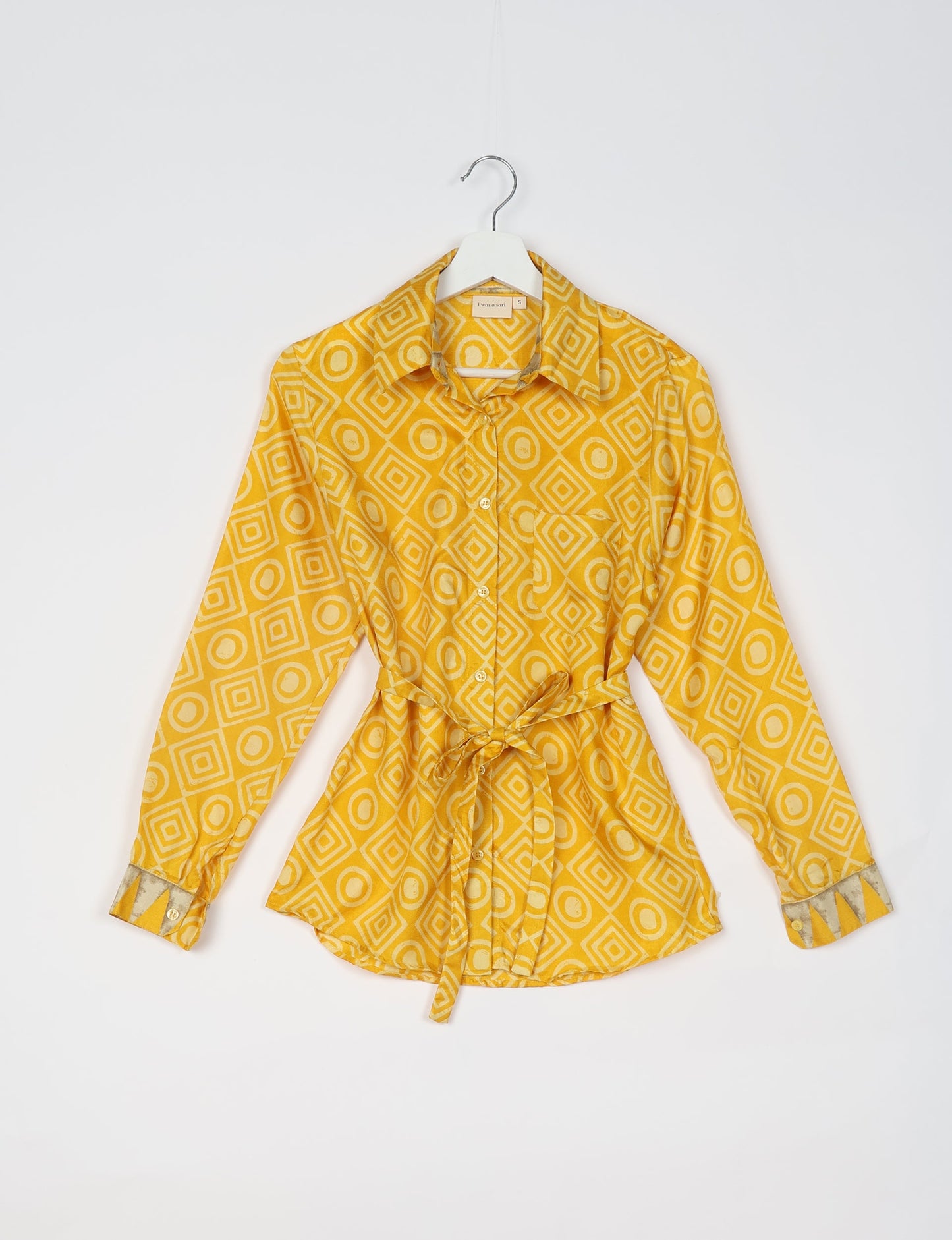 Experience sustainable fashion with our classic slim-fit shirt, crafted with ethical and green values. The shirt, designed for minimal waste, features a tie-up waist belt or neck tie, semi-spread collar, and regular shirt cuffs. Versatile and eco-friendly, wear it tucked in, unbuttoned over a tank top, or knotted at the waist for a unique style.