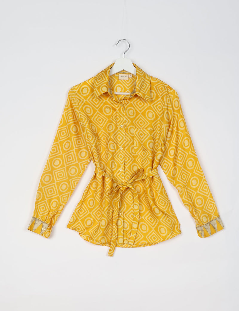 Yellow geometric patterned long-sleeve shirt with collar, front buttons, chest pocket, and waist tie, shown on hanger