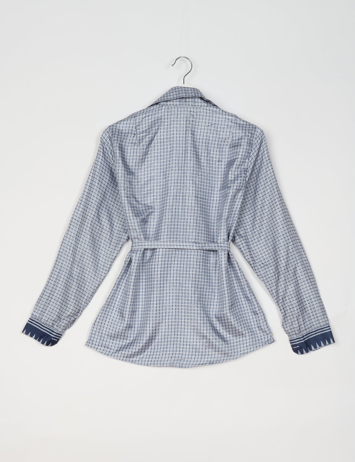 Grey geometric patterned long-sleeve shirt with dark blue cuffs and belt, shown from back on hanger against white background
