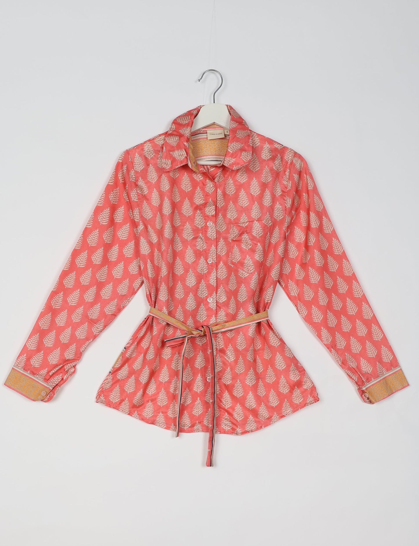 Experience sustainable fashion with our classic slim-fit shirt, crafted with ethical and green values. The shirt, designed for minimal waste, features a tie-up waist belt or neck tie, semi-spread collar, and regular shirt cuffs. Versatile and eco-friendly, wear it tucked in, unbuttoned over a tank top, or knotted at the waist for a unique style.