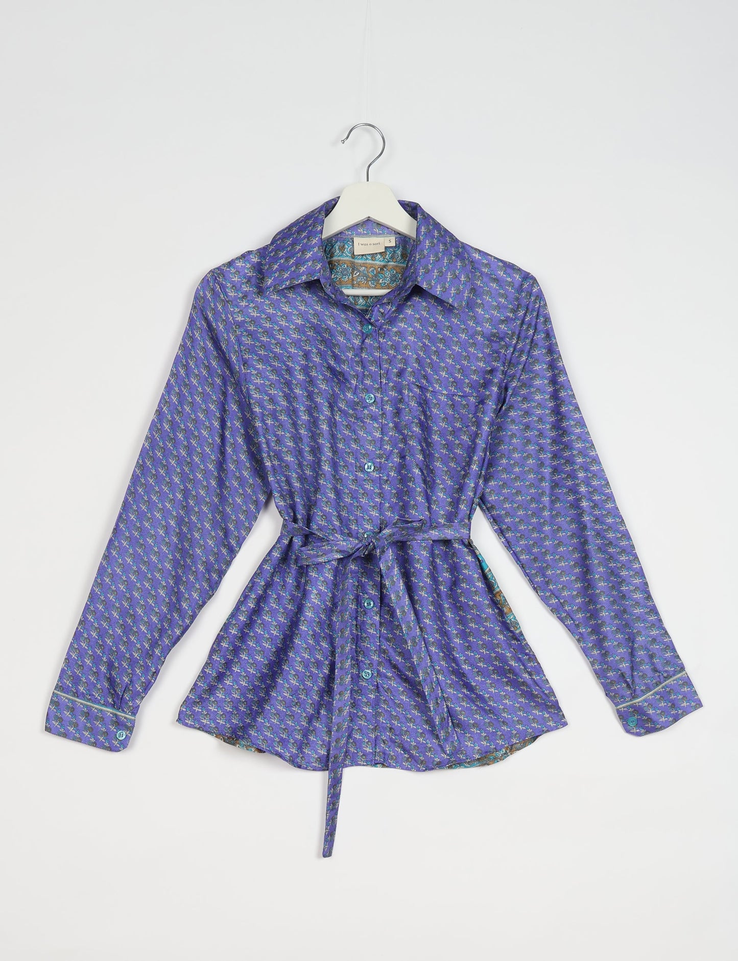 Experience sustainable fashion with our classic slim-fit shirt, crafted with ethical and green values. The shirt, designed for minimal waste, features a tie-up waist belt or neck tie, semi-spread collar, and regular shirt cuffs. Versatile and eco-friendly, wear it tucked in, unbuttoned over a tank top, or knotted at the waist for a unique style.