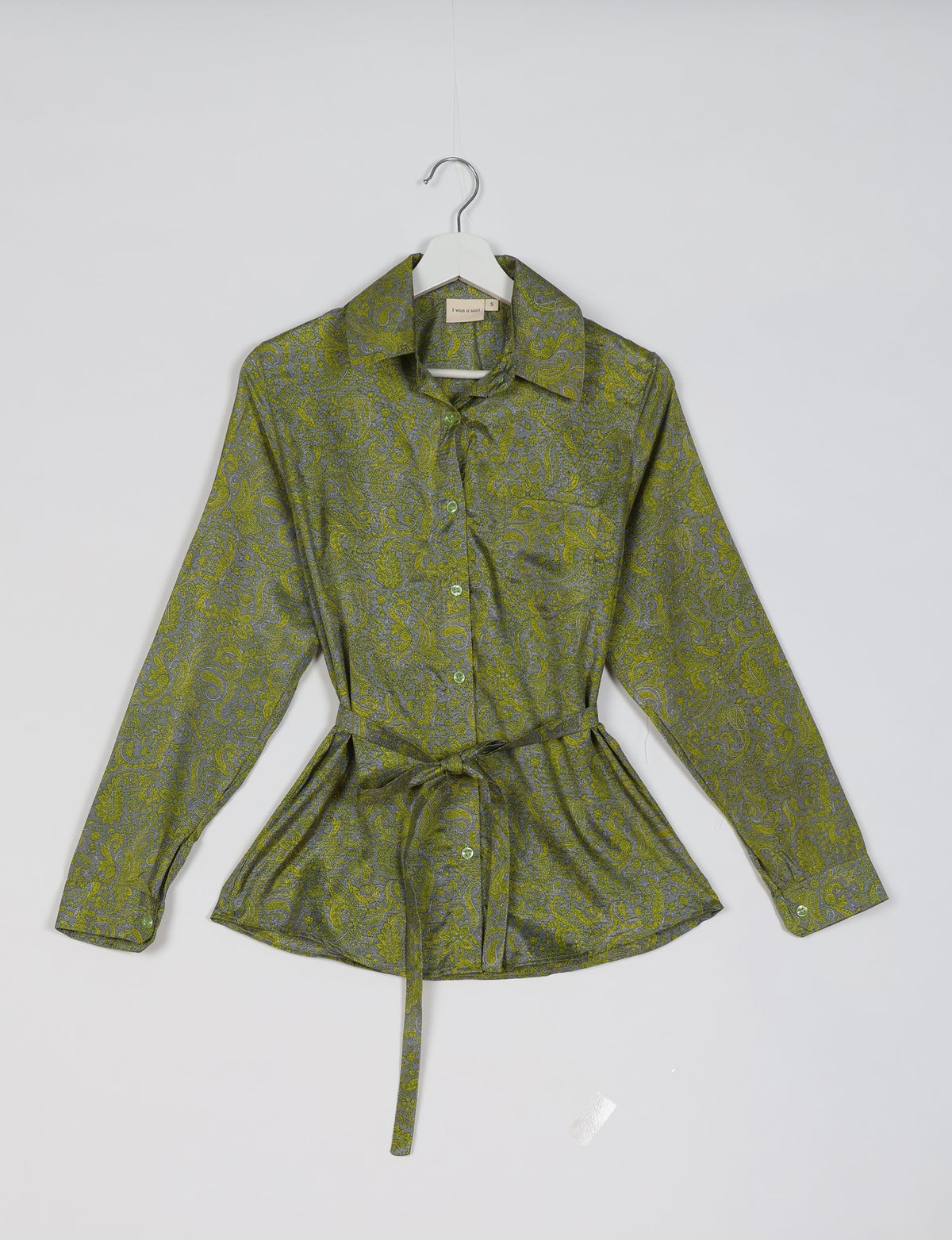 Green tropical paisley long-sleeve shirt with collar and waist tie, hanging on white hanger, front view