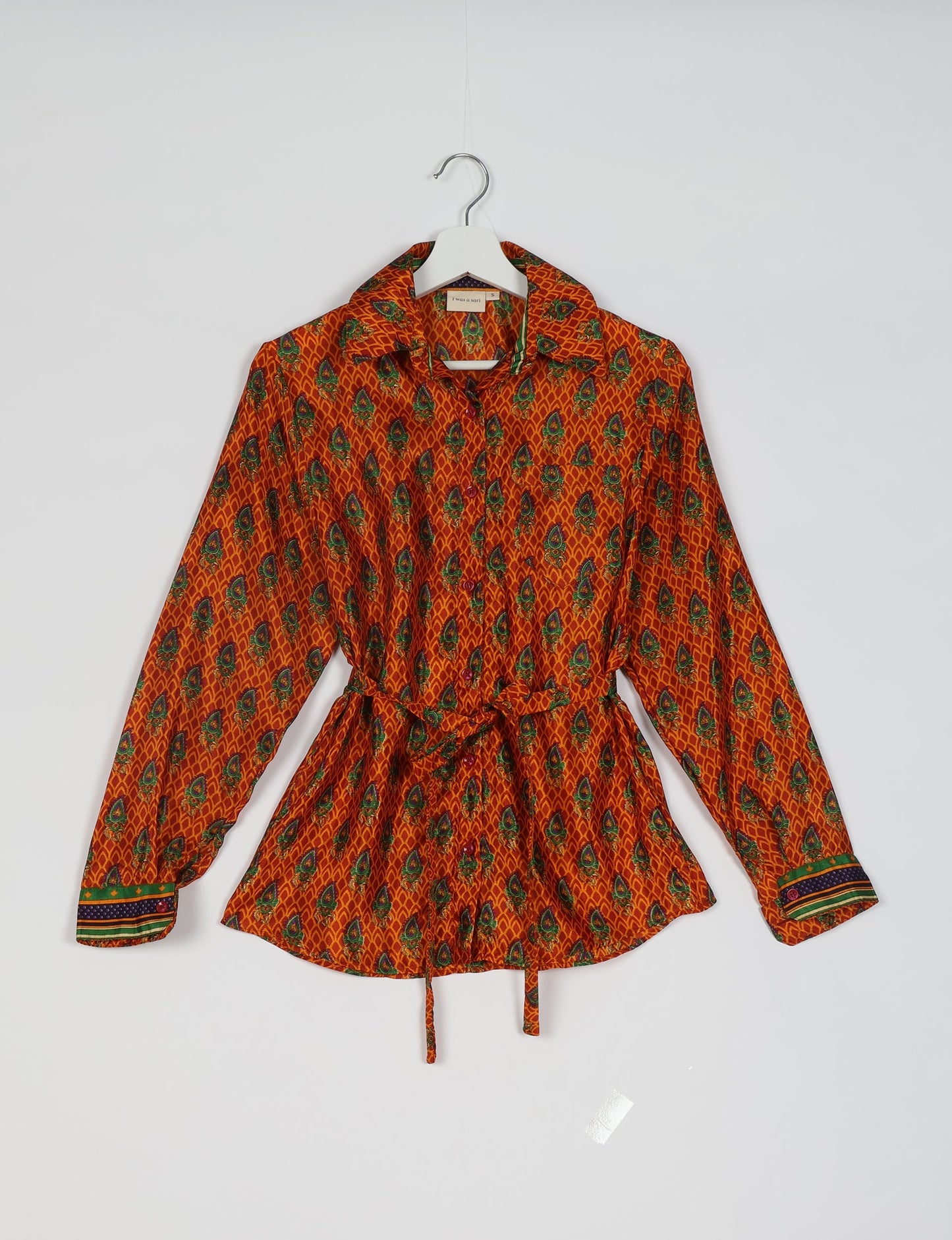 Experience sustainable fashion with our classic slim-fit shirt, crafted with ethical and green values. The shirt, designed for minimal waste, features a tie-up waist belt or neck tie, semi-spread collar, and regular shirt cuffs. Versatile and eco-friendly, wear it tucked in, unbuttoned over a tank top, or knotted at the waist for a unique style.