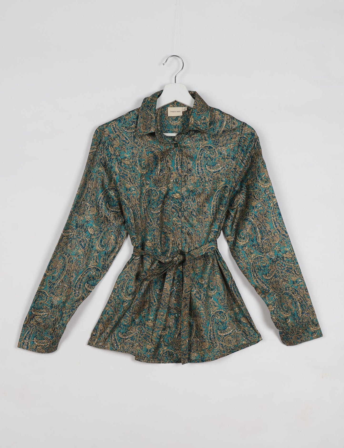 Experience sustainable fashion with our classic slim-fit shirt, crafted with ethical and green values. The shirt, designed for minimal waste, features a tie-up waist belt or neck tie, semi-spread collar, and regular shirt cuffs. Versatile and eco-friendly, wear it tucked in, unbuttoned over a tank top, or knotted at the waist for a unique style.