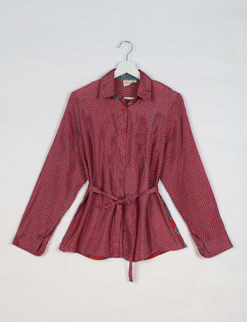 Pink geometric patterned long-sleeve shirt with collar and waist tie, hanging on a white hanger against a white background