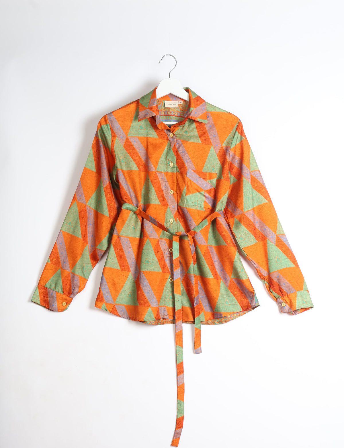 Orange geometric patterned long-sleeve shirt with collar, front buttons, chest pocket, and waist tie, shown on hanger