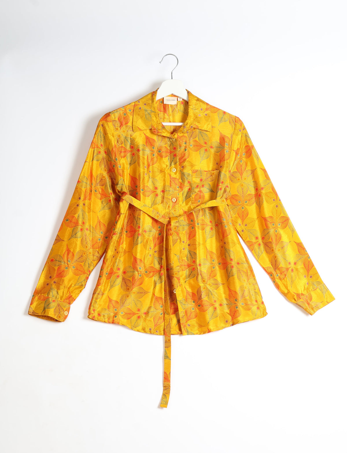 Yellow long-sleeve button-up shirt with orange and green leaf pattern, collar, and waist tie, hanging on white hanger
