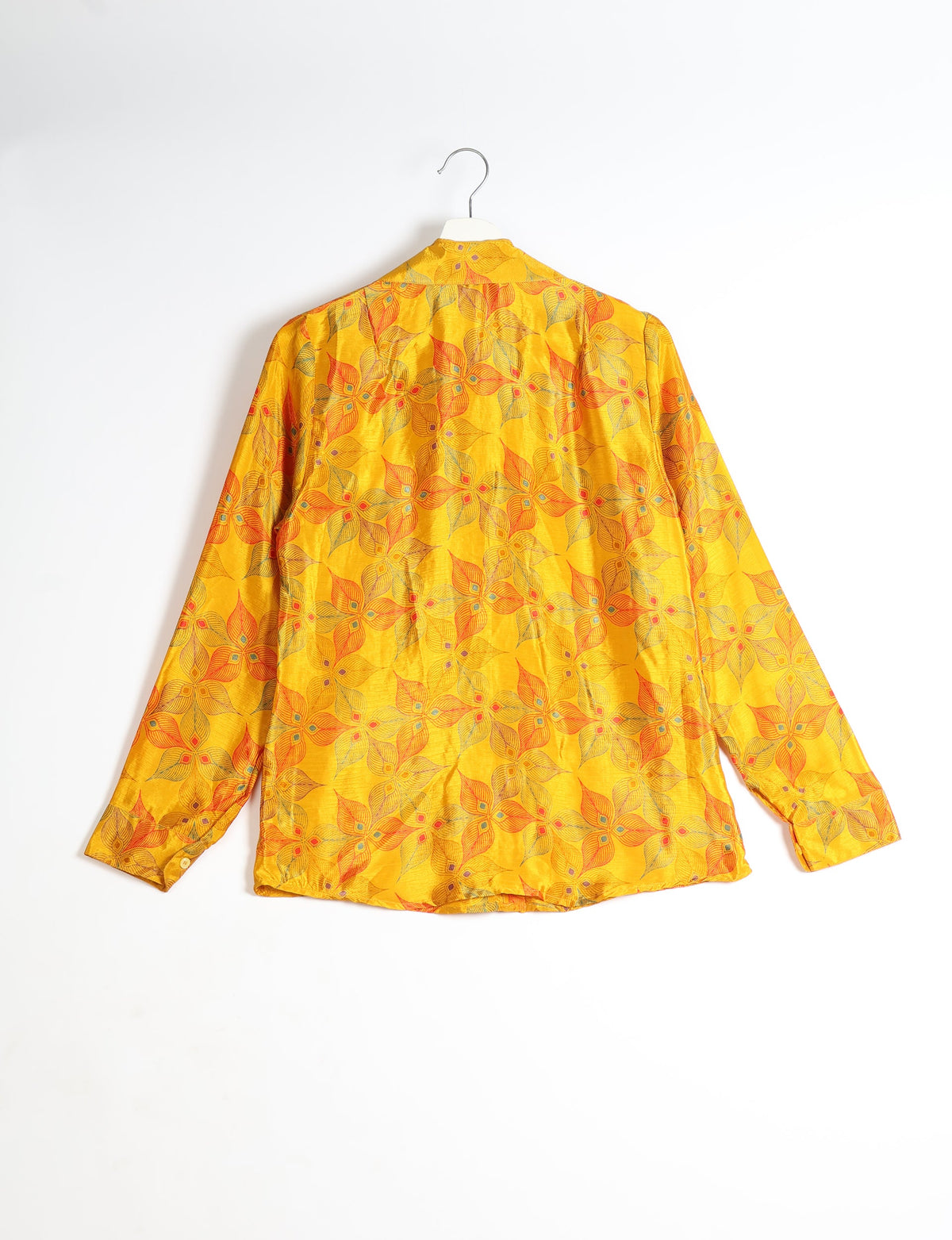 Yellow long-sleeve shirt with orange and green leaf pattern, shown from back, hanging on white hanger against white background