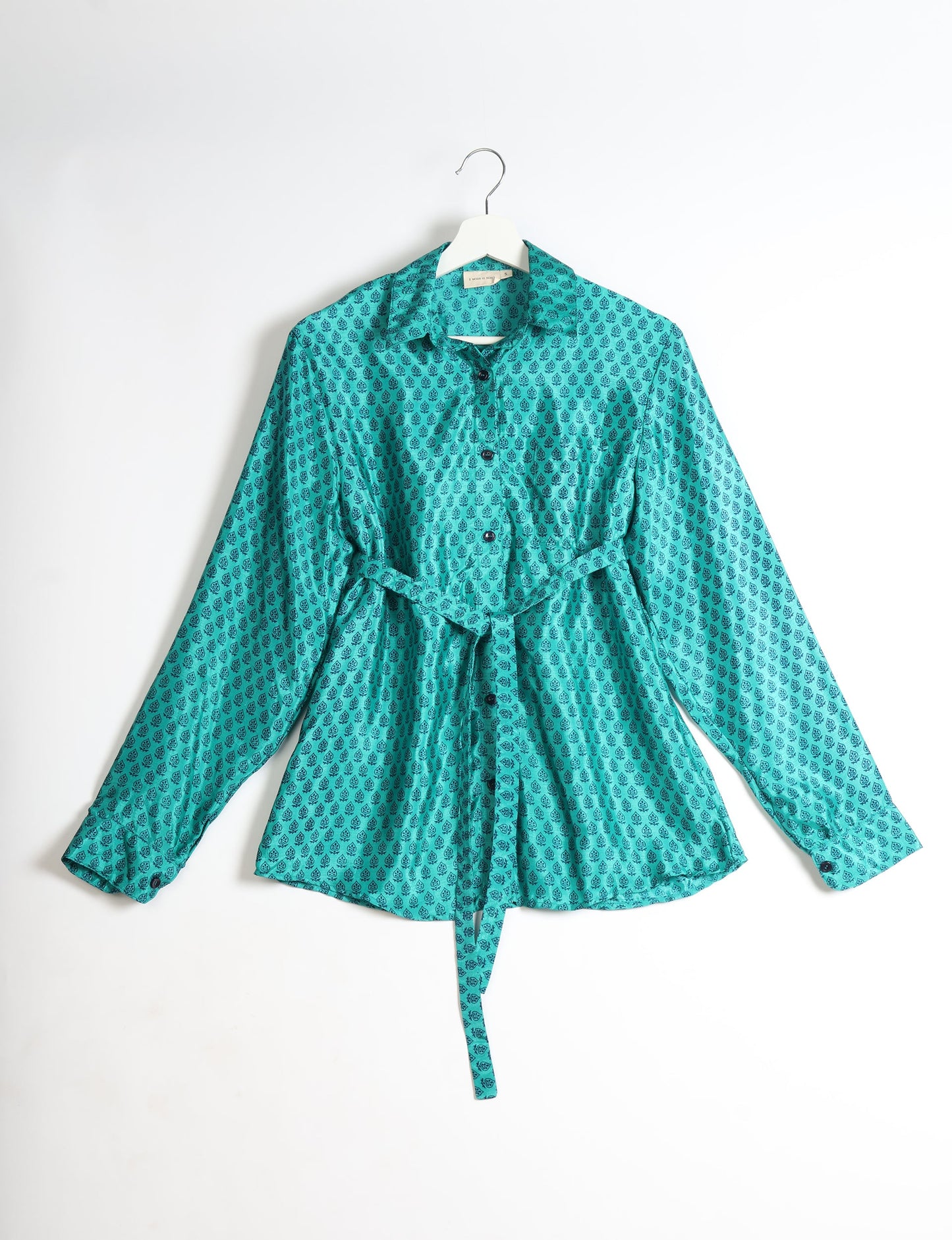 Experience sustainable fashion with our classic slim-fit shirt, crafted with ethical and green values. The shirt, designed for minimal waste, features a tie-up waist belt or neck tie, semi-spread collar, and regular shirt cuffs. Versatile and eco-friendly, wear it tucked in, unbuttoned over a tank top, or knotted at the waist for a unique style.