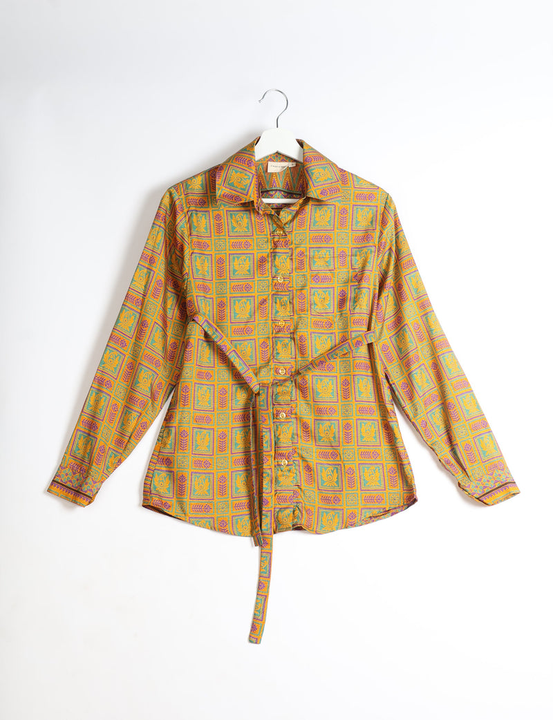 Yellow long-sleeve button-up shirt with geometric floral pattern in green and purple, hanging on white hanger, front view