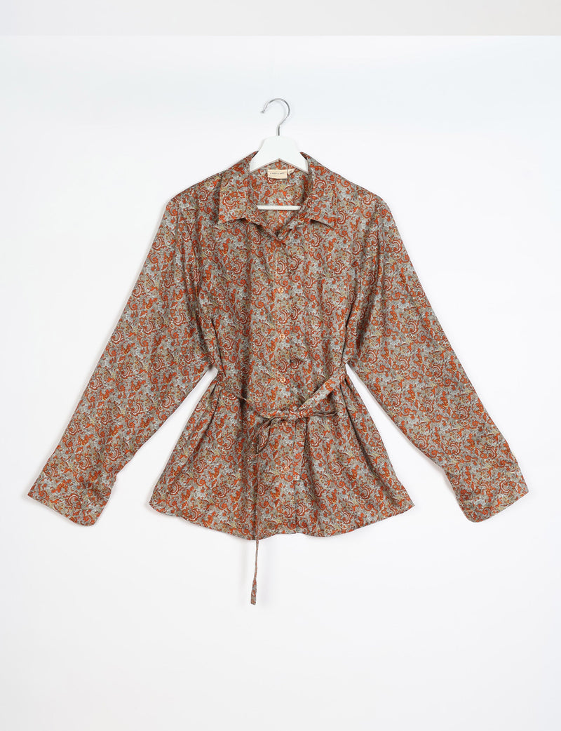 Beige tropical print long-sleeve shirt with collar, buttons down front, and waist tie, hanging on white hanger