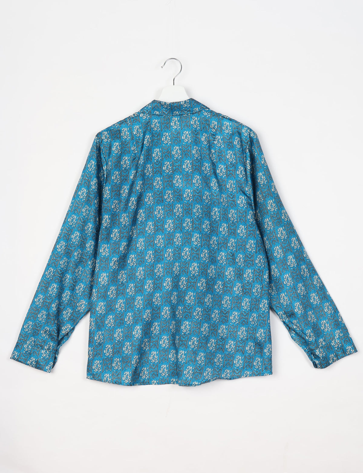 Blue long-sleeve shirt with white and dark blue tropical pattern, shown from back on white hanger against white background