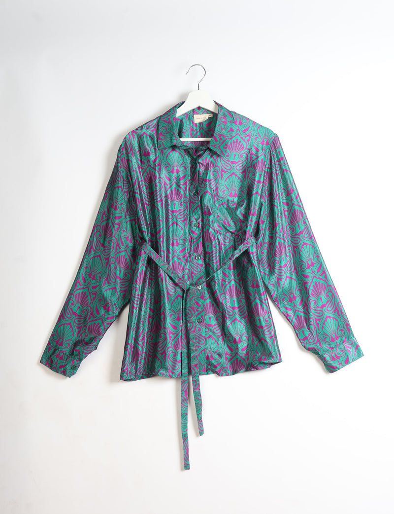 Long-sleeve button-up shirt with green and purple leaf pattern, collar, and waist tie, hanging on white hanger