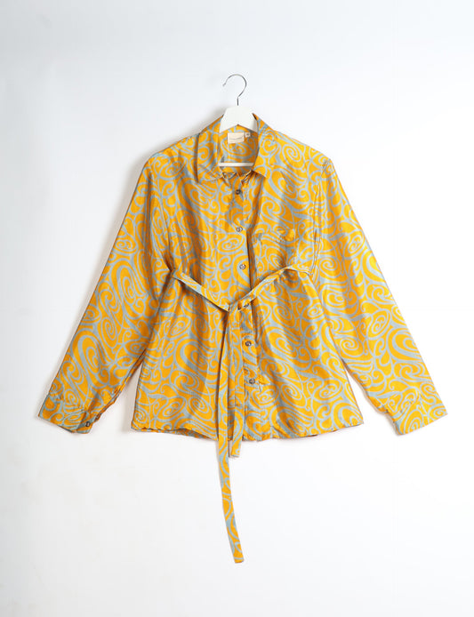 Experience sustainable fashion with our classic slim-fit shirt, crafted with ethical and green values. The shirt, designed for minimal waste, features a tie-up waist belt or neck tie, semi-spread collar, and regular shirt cuffs. Versatile and eco-friendly, wear it tucked in, unbuttoned over a tank top, or knotted at the waist for a unique style.