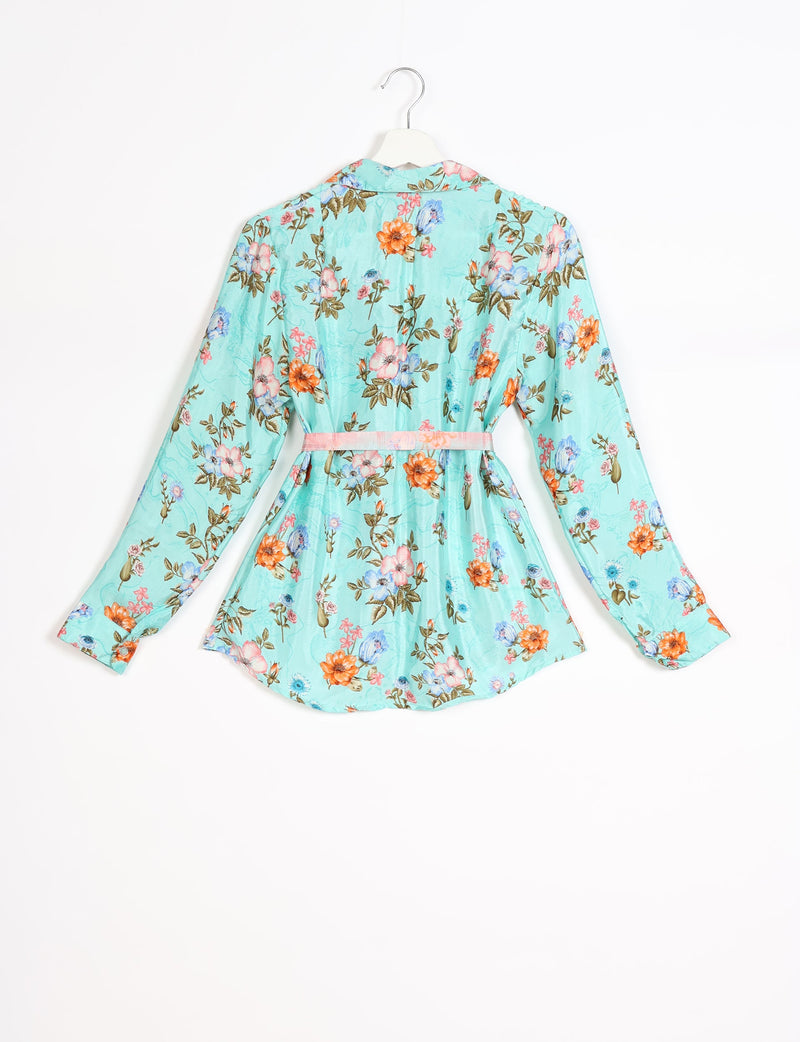 Long-sleeve green shirt with tropical floral print in orange, pink, and blue, shown from back on white hanger