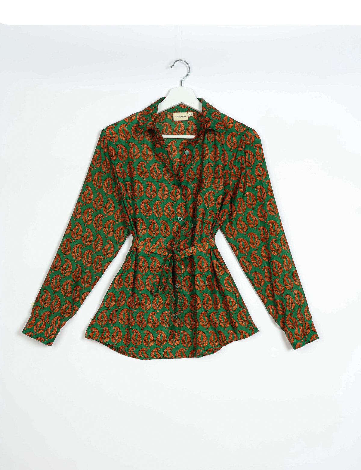 Green button-up shirt with orange leaf pattern, long sleeves, collar, and waist tie, hanging on white hanger front view
