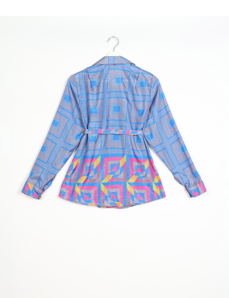 Long-sleeve blue shirt with geometric square patterns in pink, yellow, and beige, shown from back on hanger