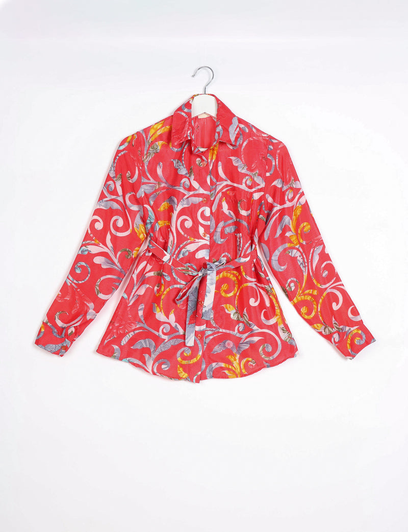Long-sleeve orange shirt with abstract multicolor swirl pattern, button front, collar, and waist tie, hanging on white hanger