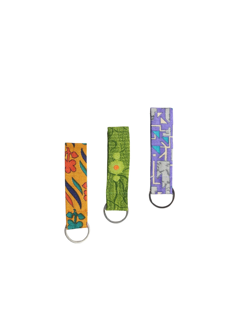 Three fabric key rings with metal rings, featuring orange floral, green botanical, and purple geometric patterns