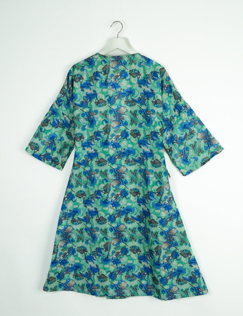 Green abstract patterned coat with blue and gray floral shapes, three-quarter sleeves, shown from back on white hanger
