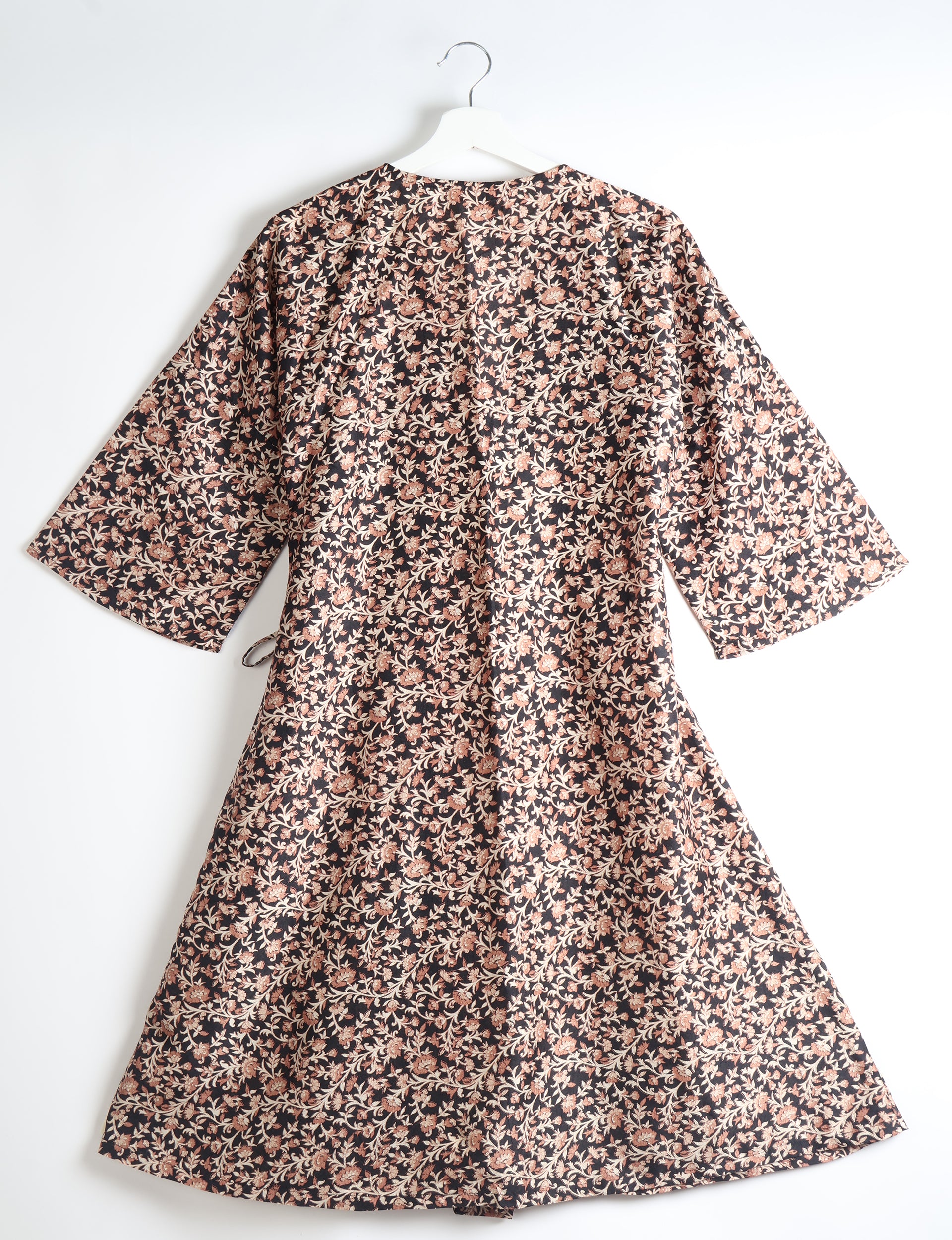 Black coat with beige and brown floral tropical print, wide sleeves, and a tie belt, shown from back on white hanger